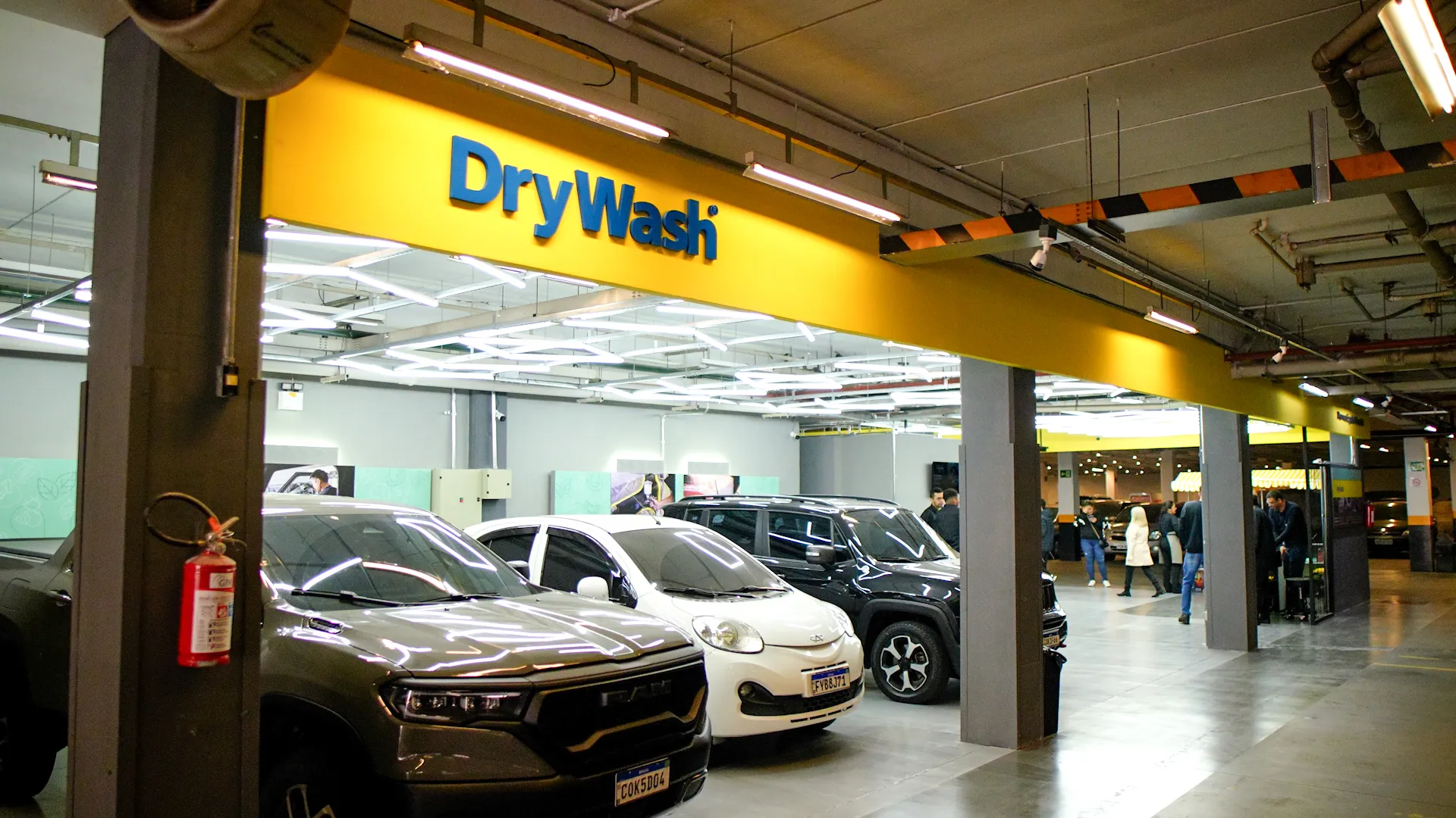 Unidade DryWash em shopping center, com veiculos em atendimento e clientes circulando