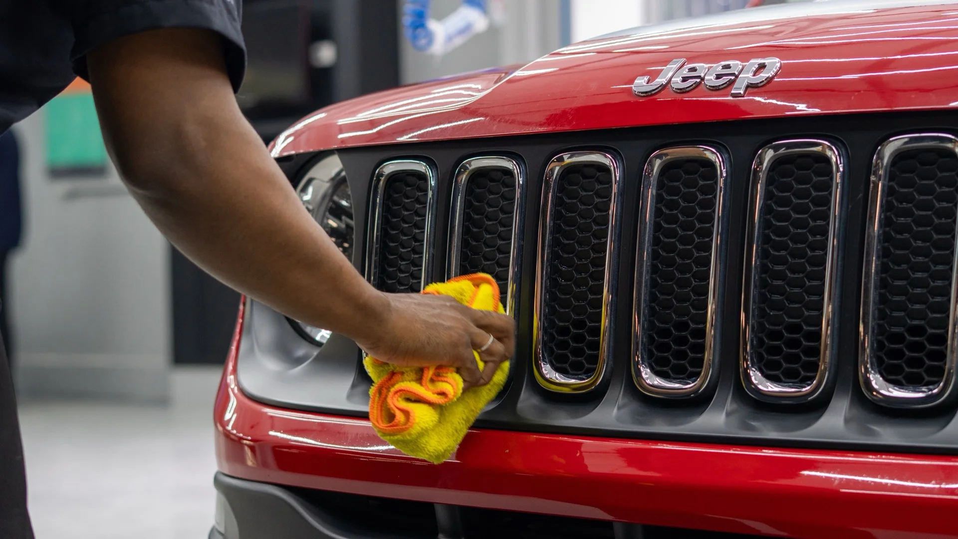Lavagem a seco em Jeep vermelho: secagem da grade frontal com microfibra